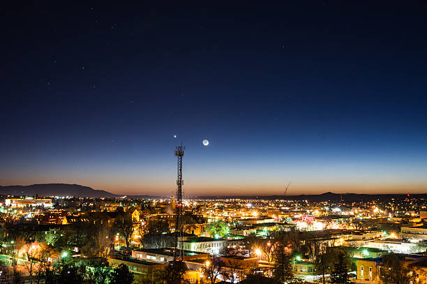 night cityscape commuincations the moon and stars stand above the lights of the city of santa fe with the sandia mountains far on the horizon.  a cellphone tower sticks up into the sky and contrasts the scenery.  horizontal composition taken at christmas time in santa fe, new mexico.   santa fe new mexico mountains stock pictures, royalty-free photos & images