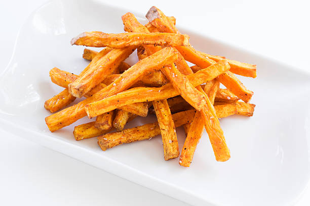 sweet potato fries on white Baked sweet potato fries on a white platter. sweet potato french fries stock pictures, royalty-free photos & images