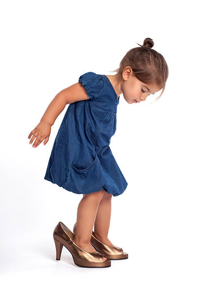 милая маленькая девочка с большим туфли на высоком каблуке - little girls pre adolescent child standing isolated стоковые фото и изображения