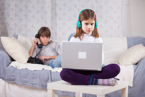 Girl and boy using phone and laptop