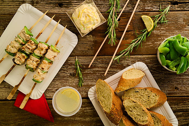 Concept of barbecue picnic food. Barbecue grilled chicken and pepper kebab or souvlaki on skewer served on cardboard plate in rustic environment. Selective focus.