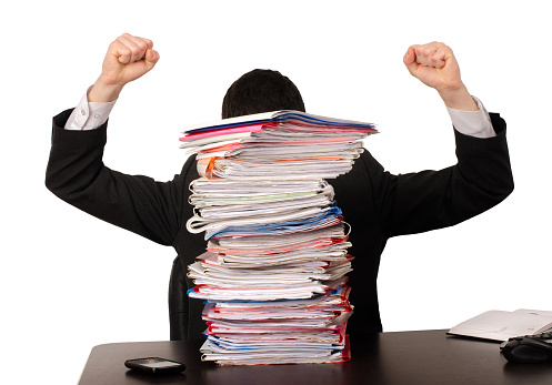 Unhappy worker with a big pile of files to work on. Isolated on white.