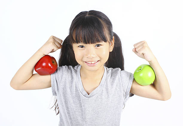 istock Little girl flexes her muscle with two apples 485414796