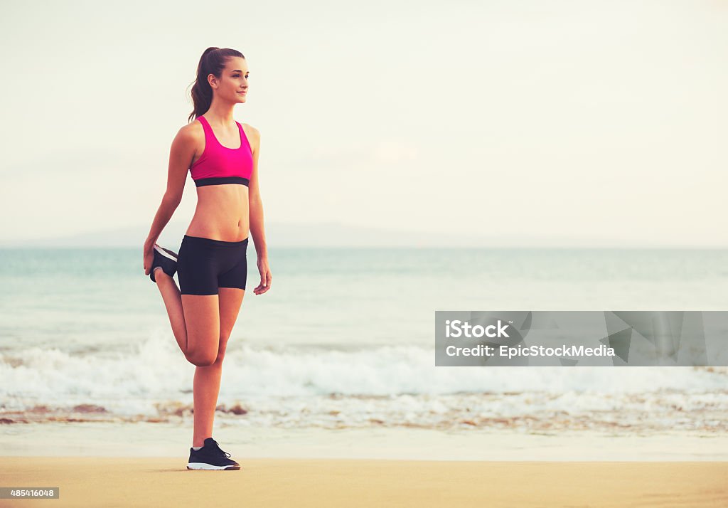 Fitness Woman Stretching Healthy Active Lifestyle. Young fitness woman stretching on the beach at sunset. 2015 Stock Photo