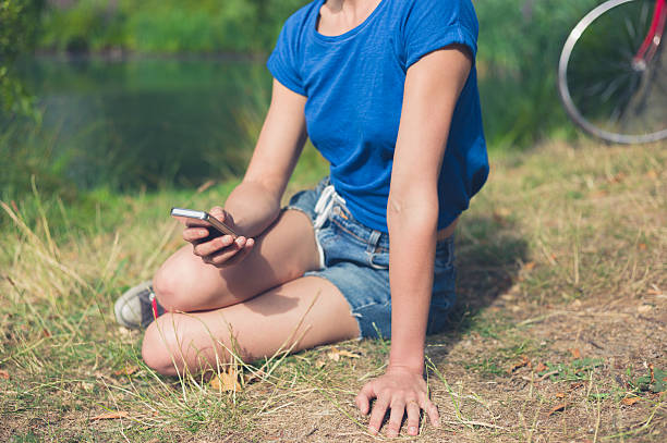 istock Young woman using smart phone by water in park 485417848