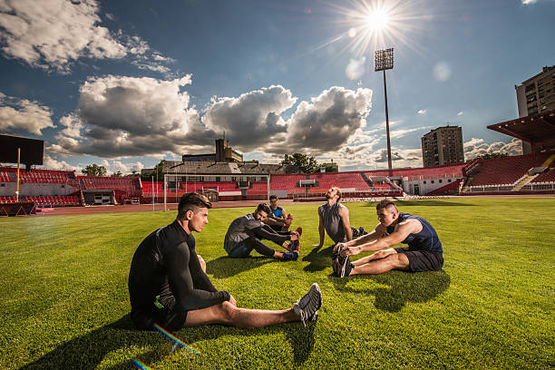 istock Group of young athletes doing relaxation exercises on grass. 485422356