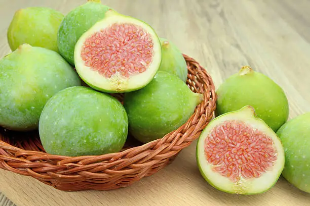 Figs into the wicker basket on a cutting board