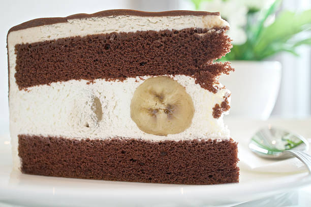 Piece of chocolate with banana cake on a white plate at table.