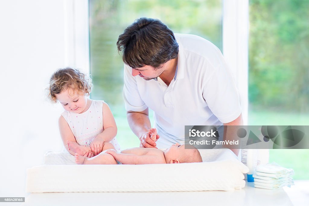 Chica niño encantadores ayudar a padre de su hermano cambiar los pañales - Foto de stock de Adulto libre de derechos