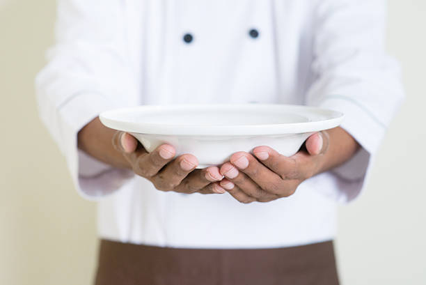 istock Indian male chef in uniform presenting an empty plate 485435352