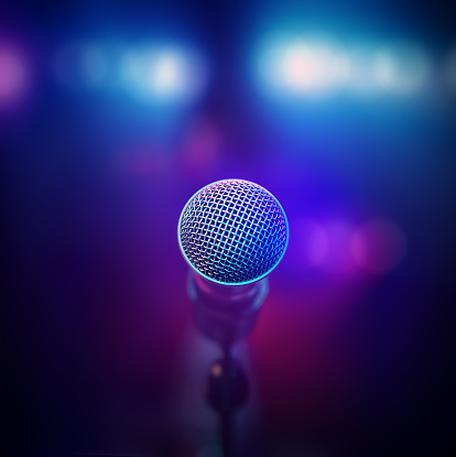 Musical microphone close-up from behind facing out of focus stage lights