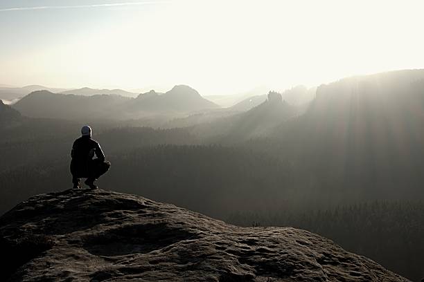 istock Hiker sits on a rocky peak and enjoy mountains scenery 485439376