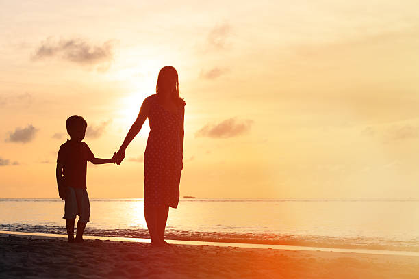 istock mother and son walking on sunset beach 485439844