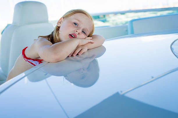 Young girl, leaning on a table on a yacht. She is bored. She is looking at camera.