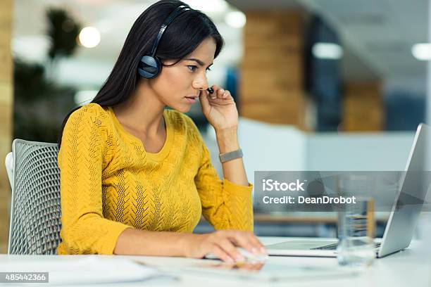 Businesswoman In Headphones Using Laptop Stock Photo - Download Image Now - 2015, Adult, Business