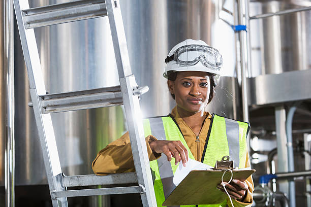 istock Black woman working in factory with clipboard, hardhat 485445470