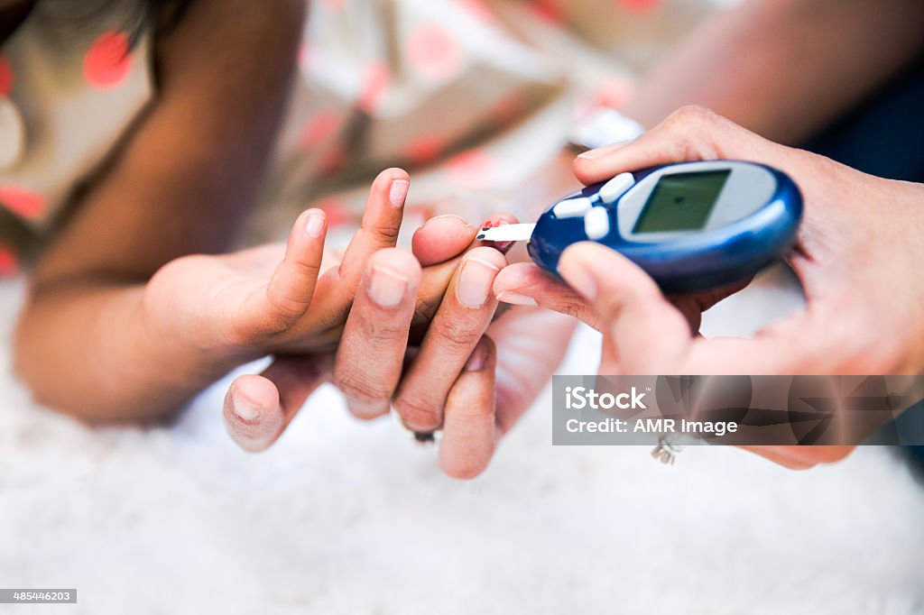 Type 1 Diabetes management Mother is checking her daughters' diabetes by monitoring blood glucose. Diabetes Stock Photo
