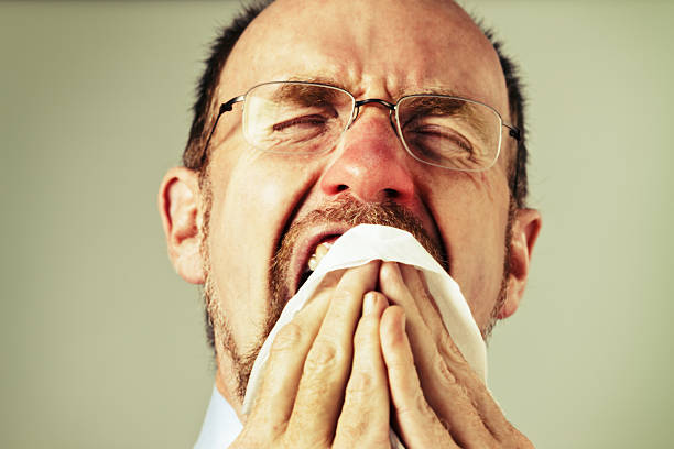 istock Aaachoo! Red-nosed man suffering from a cold sneezes into handkerchief 485446565