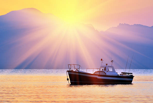 Old fishing boat in the bay at sunrise against mountains