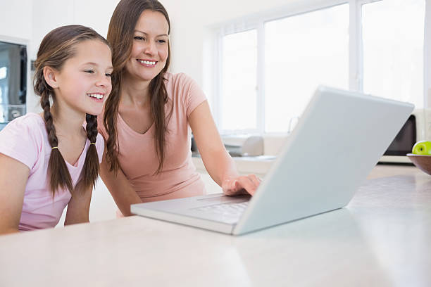 istock Mother with young daughter using laptop in kitchen 485448751