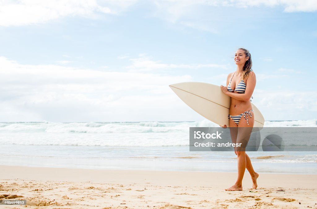 Woman surfing at the beach Happy woman surfing at the beach and carrying her surfboard Adult Stock Photo