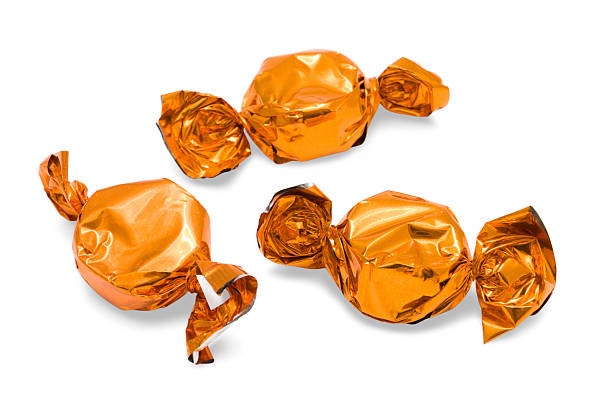 istock Sweets in orange foil wrappers on isolated a white background 485450379