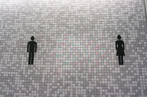 Toilet sign with male and female on grey and white mosaic wall