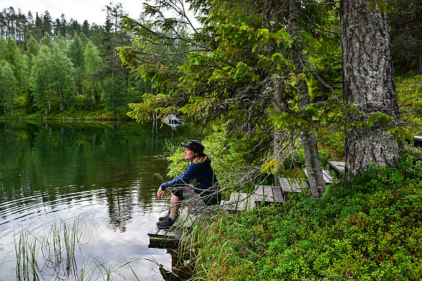 istock Woman sitting on lake pier 485458090