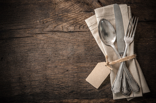 Vintage silverware with an empty tag on rustic wooden background