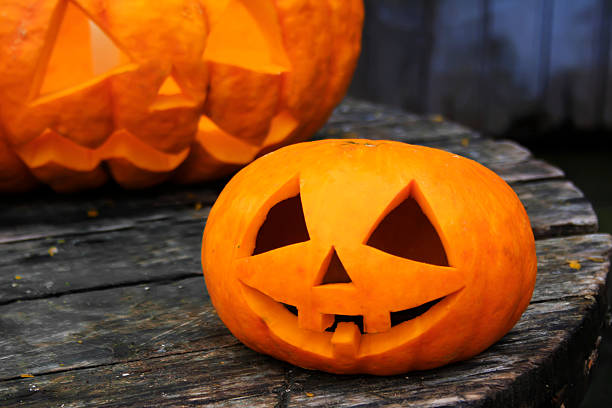 istock Two jack-o'-lantern on an old wooden table. 485462042