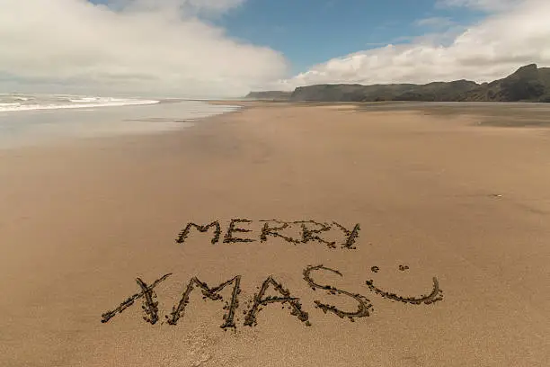 merry xmas handwritten in sand on Karekare beach, New Zealand