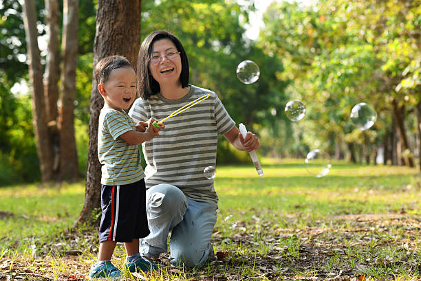 istock Asian child playing bubble wand with mother 485465120