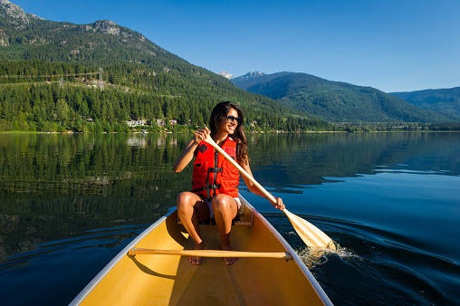 Female paddling a canoe on a prisitine mountain lake