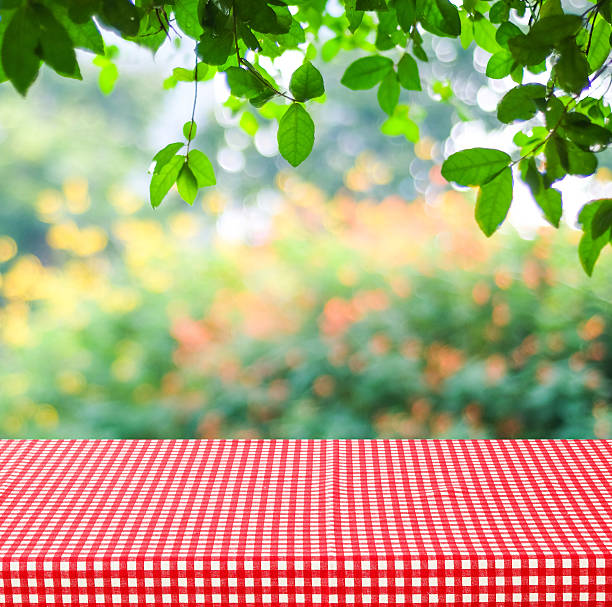istock Empty table and red tablecloth with blur green leaves 485468798