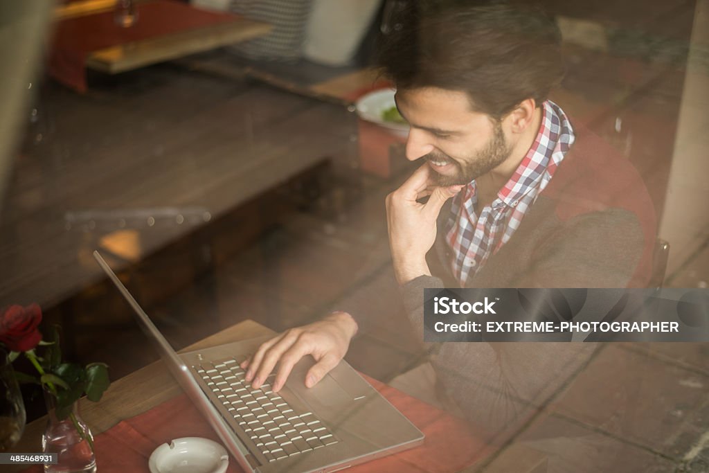 Remote office Man behind the restaurant window working on his lap top computer. Adult Stock Photo