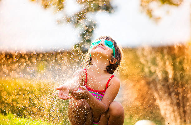 Cute little girl having fun outside Cute little girl having fun outside in summer garden sprinkler stock pictures, royalty-free photos & images