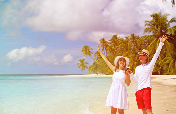 istock happy loving couple drinking wine at beach 485471652