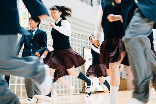 Japanese teenage students in uniforms running to School recess