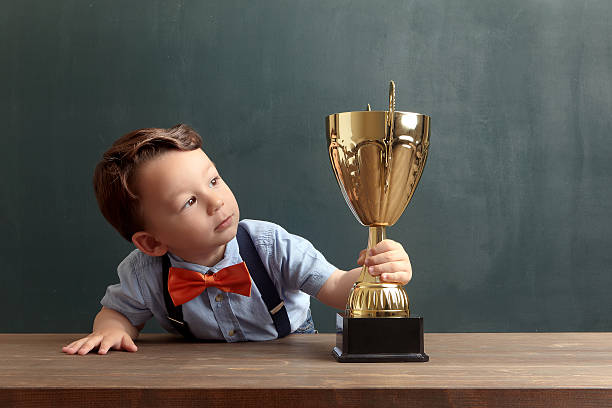 istock Little boy holding and looking towards a golden trophy 485474976