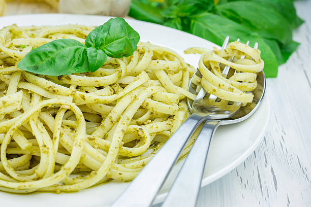Tagliatelle pasta with pesto sauce on a white plate stock photo
