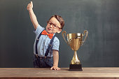 Little boy showing his thumb up with a golden trophy