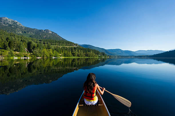 Female paddling a canoe on a prisitine mountain lake