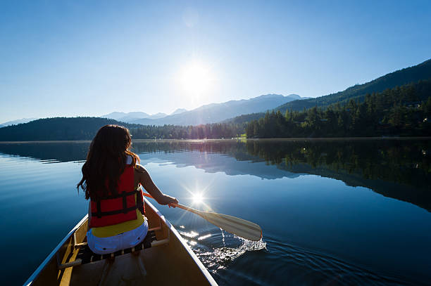 Female paddling a canoe on a prisitine mountain lake