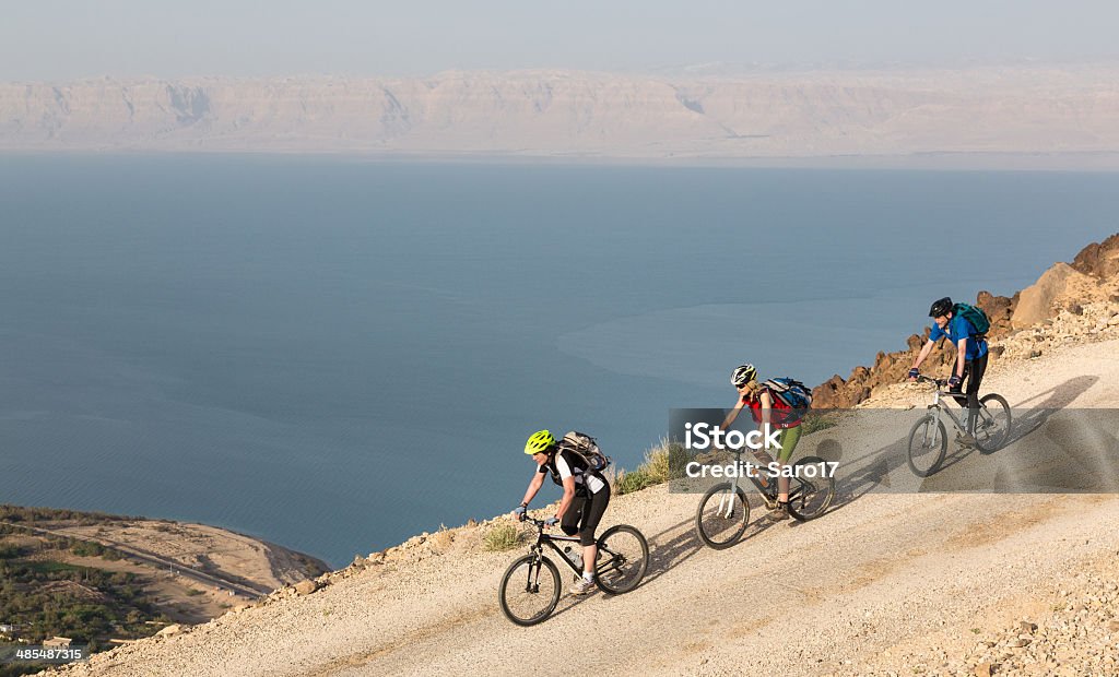 Dead Sea Downhill, Jordan Three Mountainbikers on their way down to the Jordan coastline of the Dead Sea. Its surface and shores are 427 metres (1,401 ft) below sea level, Earth's lowest elevation on land. The Dead Sea is 306 m (1,004 ft) deep, the deepest hypersaline lake in the world. With 34.2% salinity (in 2011), it is also one of the world's saltiest bodies of water. In the misty distance the Israeli coastline is visible. Dead Sea Stock Photo