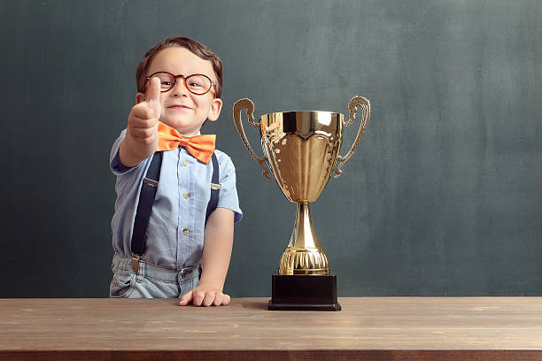 istock Little boy showing his thumb up with a golden trophy 485487560