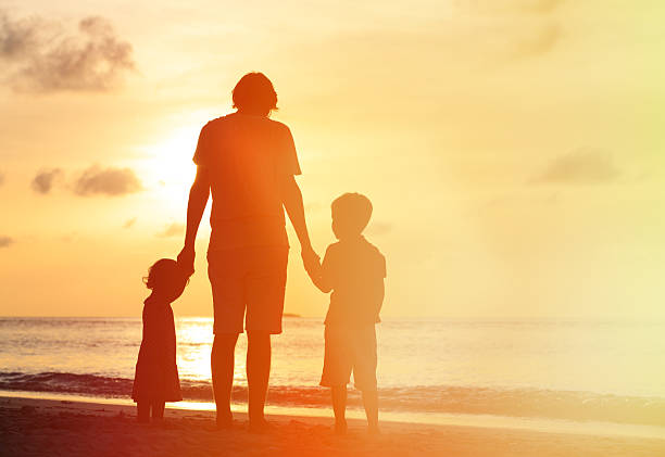 istock father and two kids walking on sunset beach 485488348