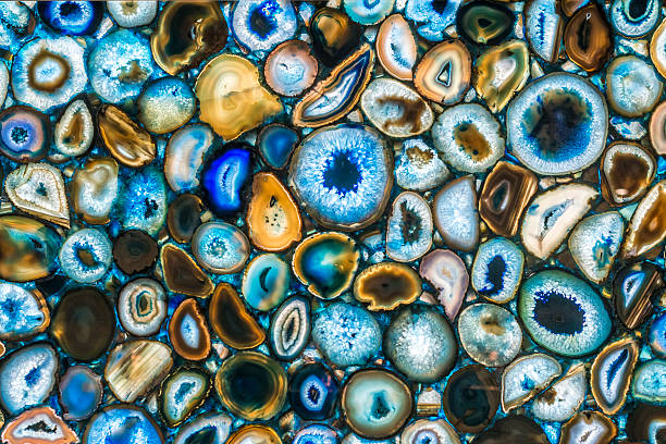 Many geode of agathe, turquoise, orange, red, blue, yellow, white, green. Abstract background. Vibrant colors. Backlit section of colorful geodes of agathe