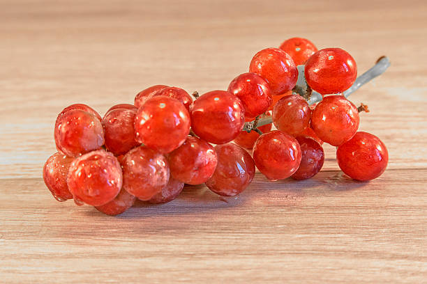 grapes Grapes lying on a wooden surface, with a spider crawing accross them animall stock pictures, royalty-free photos & images