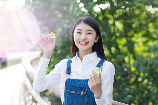 beautiful girl in the sun, happy blowing bubbles