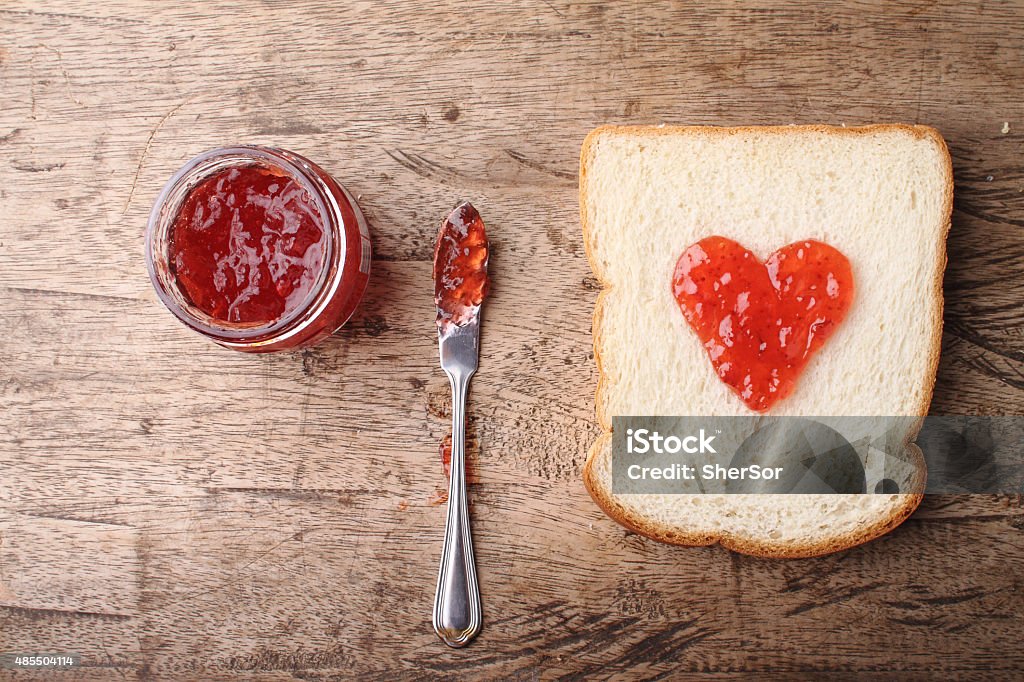 slice of bread with strawberry jam in heart shape slice of bread with strawberry jam in heart shape on wooden board Bread Stock Photo